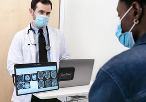 12.5-inch | 14-inch | Swivel | Sidetrak | Monitor Portable | Dr. standing at a portable table looking at his laptop while showing a patient x-rays on a sidetrak swivel rotated 180