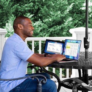 College student working at an outdoor table using a sidetrak swivel portable monitor while working on class assignments